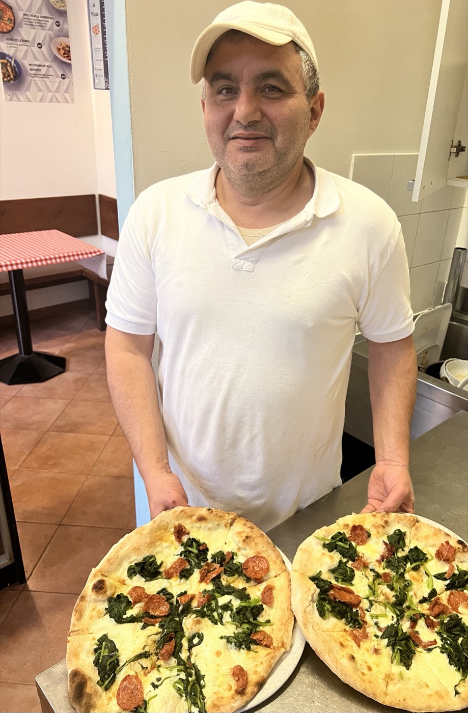 Vincenzo con due pizze appena sfornate, nel locale di Via Carloni